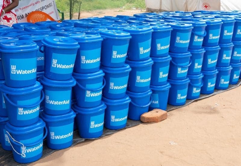 Picture of rows of blue hygiene kit buckets, with lids. Branded with WaterAid label.